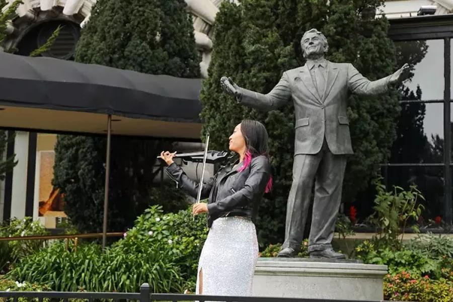 A woman plays the violin in front of the Tony Bennett statue at the 费尔蒙酒店.